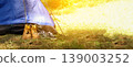 Tourist boots and sneakers standing near a blue tent in a forest. Concept of camping, hiking, and outdoor summer adventures. Panoramic shot with bright sunlight and copy space 139003252