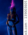 Sensual woman in chainmail lingerie surrounded by pink smoke under blue neon light 139003605