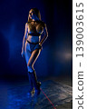 Woman in futuristic chainmail armor and boots posing in dramatic blue light with red laser 139003615