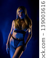 Futuristic portrait of confident woman in gold chainmail fashion under blue neon light 139003616