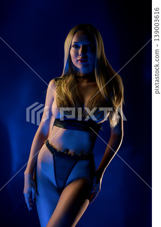 Futuristic portrait of confident woman in gold chainmail fashion under blue neon light Futuristic portrait of confident woman in gold chainmail fashion under blue neon light 139003616