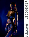 Futuristic portrait of alluring woman in black and gold outfit with laser light 139003617