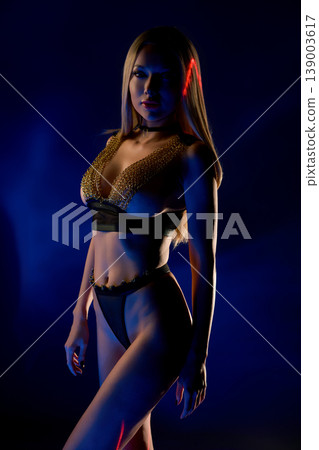 Futuristic portrait of alluring woman in black and gold outfit with laser light Futuristic portrait of alluring woman in black and gold outfit with laser light 139003617
