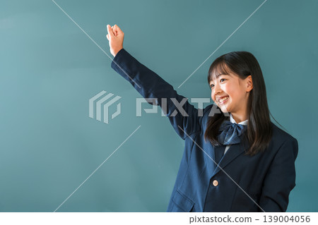 Female elementary, junior high, and high school students in blazers standing in front of the blackboard and making a fist pump Female elementary, junior high, and high school students in blazers standing in front of the blackboard and making a fist pump 139004056