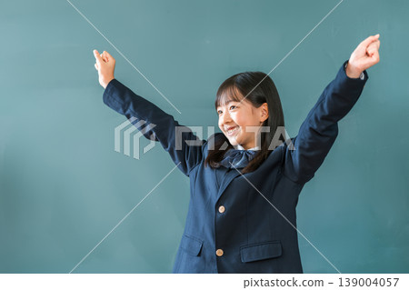 Female elementary, junior high, and high school students in blazers standing in front of the blackboard and making a fist pump Female elementary, junior high, and high school students in blazers standing in front of the blackboard and making a fist pump 139004057