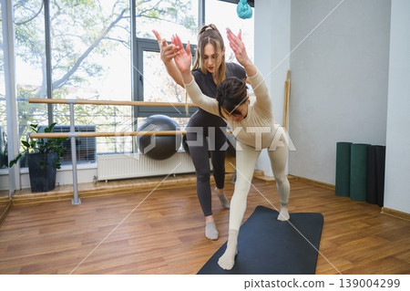 Female trainer correcting posture of young woman during workout. Female trainer correcting posture of young woman during workout. 139004299
