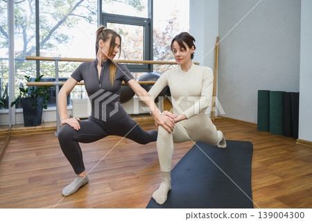 Female trainer correcting posture of young woman during workout. 139004300
