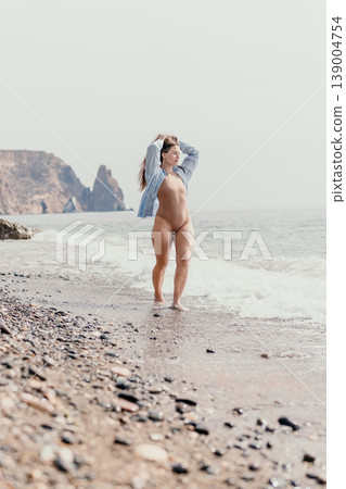 Woman beach swimsuit young female in beige bodysuit walking on pebbled shore by the sea with rocky cliffs under a bright sky Woman beach swimsuit young female in beige bodysuit walking on pebbled shore by the sea with rocky cliffs under a bright sky 139004754