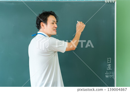 Male teacher giving a lesson in front of the blackboard Male teacher giving a lesson in front of the blackboard 139004867