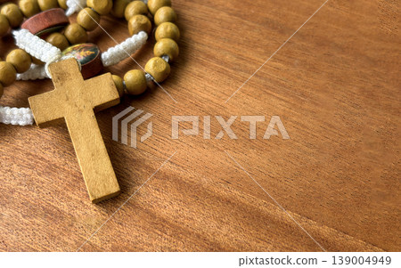 Wooden cross and rosary beads on wooden tabletop representing religious faith prayer tradition and inner peace. 139004949
