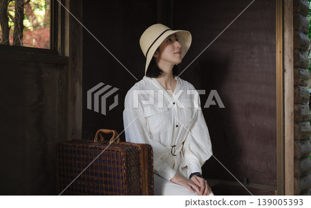 A woman waiting for a train on the platform of a rural station 139005393