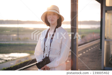 A woman waiting for a train on the platform of a rural station A woman waiting for a train on the platform of a rural station 139005402