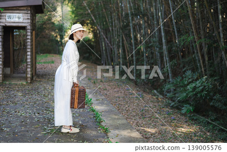 A woman waiting for a train on the platform of a rural station A woman waiting for a train on the platform of a rural station 139005576
