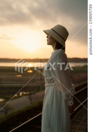 A woman waiting for a train on the platform of a rural station 139005789