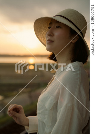 A woman waiting for a train on the platform of a rural station 139005791
