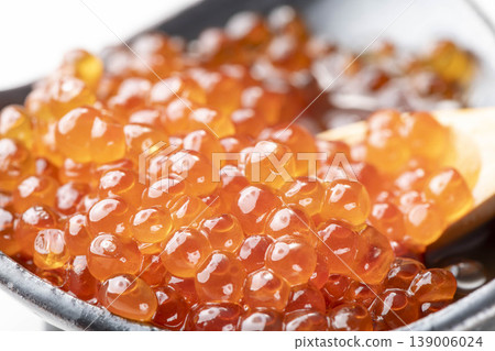 A close-up of salmon roe marinated in soy sauce, served on a spoon. The plump, glistening salmon eggs are beautiful, and it's high-quality salmon roe from Hokkaido. 139006024