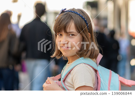 Girl 7 years old walking with backpack looking back in urban scene Girl 7 years old walking with backpack looking back in urban scene 139006844