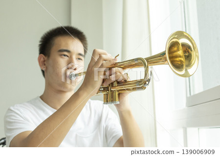 Teenage boy Learning To Play Trumpet In home school. Teenage boy Learning To Play Trumpet In home school. 139006909