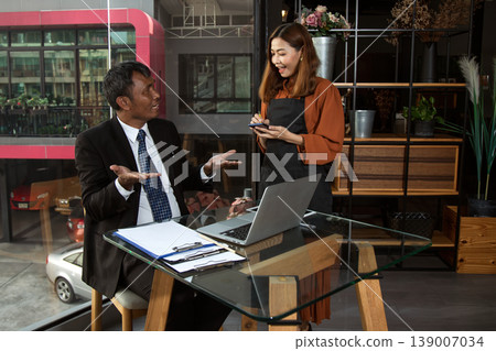 Businessman talking with waitress taking order in modern cafe, service and customer communication concept, showcasing hospitality industry, teamwork and professional interaction in casual workspace 139007034