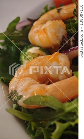 Fresh shrimp placed on a bed of mixed greens with colorful vegetables, showcasing the vibrant textures and colors of a nutritious seafood salad 139007110