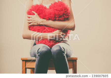 Sad unhappy woman holding red heart pillow Sad unhappy woman holding red heart pillow 139007605