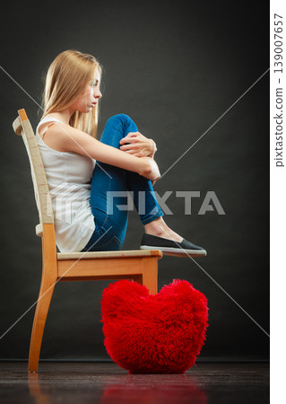 Sad unhappy woman with red heart pillow Sad unhappy woman with red heart pillow 139007657