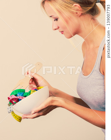 Diet. Girl with colorful measuring tapes in bowl Diet. Girl with colorful measuring tapes in bowl 139007793