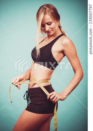 Fitness girl measuring her waistline Fitness girl measuring her waistline 139007797