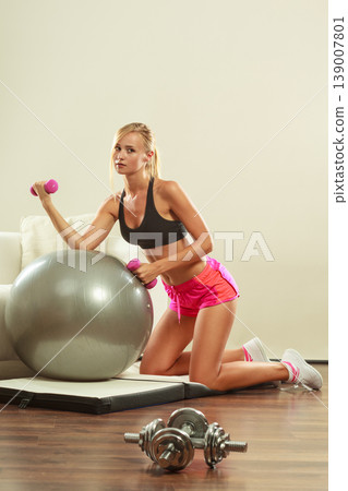 Woman with gym ball and dumbbell doing exercise Woman with gym ball and dumbbell doing exercise 139007801