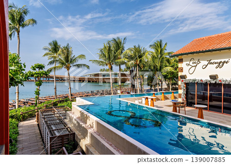 Phu Quoc, Vietnam - January 3 2026: Tropical Resort Poolside View with Palm Trees Phu Quoc, Vietnam - January 3 2026: Tropical Resort Poolside View with Palm Trees 139007885