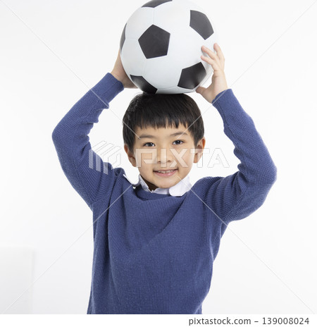 Happy boy holding football ball with his hands Happy boy holding football ball with his hands 139008024