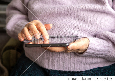 Elderly woman using tablet at home focusing on hands and touchscreen for digital communication and learning Elderly woman using tablet at home focusing on hands and touchscreen for digital communication and learning 139008186