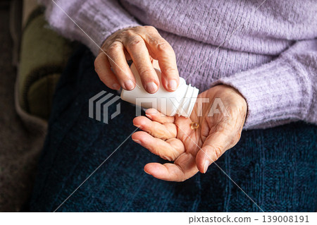 Elderly woman taking medication from a white pill bottle into her hand at home Elderly woman taking medication from a white pill bottle into her hand at home 139008191