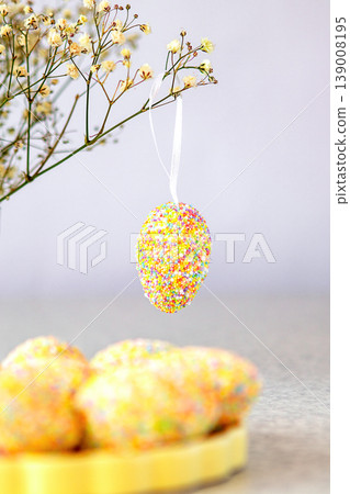 Pastel Easter egg decoration with multicolor sprinkles hanging from a delicate floral branch Pastel Easter egg decoration with multicolor sprinkles hanging from a delicate floral branch 139008195