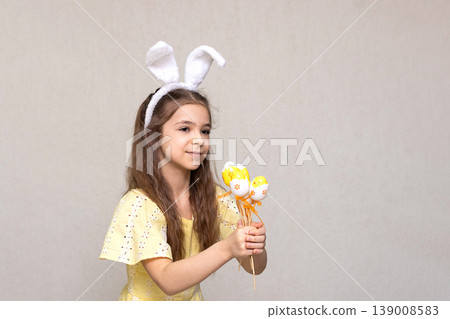 Young girl wearing bunny ears and yellow dress holding an Easter egg bouquet for spring celebration Young girl wearing bunny ears and yellow dress holding an Easter egg bouquet for spring celebration 139008583