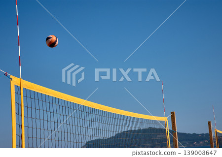 Volleyball in the air over a yellow net during a beach match in Baiona under a clear blue sky Volleyball in the air over a yellow net during a beach match in Baiona under a clear blue sky 139008647