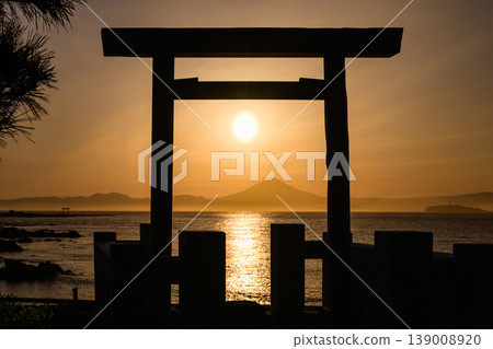 The setting sun is about to sink behind Mount Fuji, visible beyond the torii gate. The setting sun is about to sink behind Mount Fuji, visible beyond the torii gate. 139008920