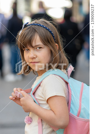 Portrait of child with backpack among people with attentive look Portrait of child with backpack among people with attentive look 139009237