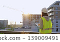 Construction female engineer taking notes and tapping on tablet computer while inspecting a building site at sunset. Industry development concept 139009491