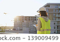 Woman construction engineer is taking notes with a tablet pc while inspecting a construction site at sunset 139009499