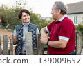 Positive mature man and woman standing near fence in garden 139009657