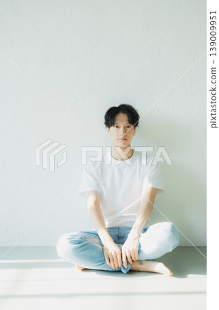 一個穿著牛仔褲的男人坐在地板上 139009951