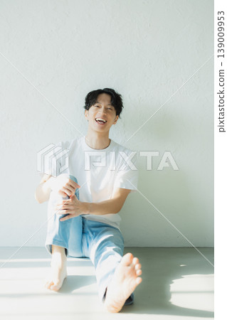一個穿著牛仔褲的男人坐在地板上 一個穿著牛仔褲的男人坐在地板上 139009953