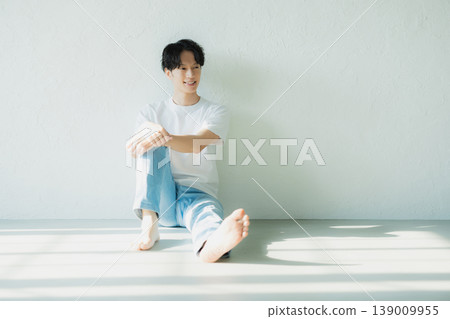 一個穿著牛仔褲的男人坐在地板上 一個穿著牛仔褲的男人坐在地板上 139009955