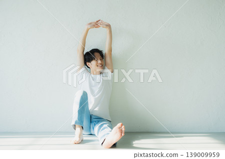 一個穿著牛仔褲的男人坐在地板上 一個穿著牛仔褲的男人坐在地板上 139009959