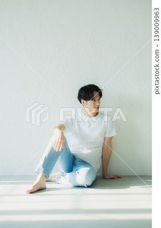 一個穿著牛仔褲的男人坐在地板上 一個穿著牛仔褲的男人坐在地板上 139009963