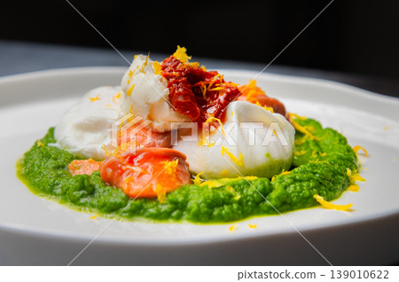 Poached eggs with salmon, spinach, and sun-dried tomatoes on a plate 139010622