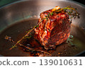Beef roast with herbs resting in a metal pan, glistening with juices 139010631