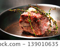 Beef roast with herbs and garlic cooking in a frying pan on stovetop 139010635
