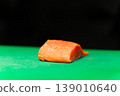 Fresh salmon fillet piece on green cutting board with dark background 139010640